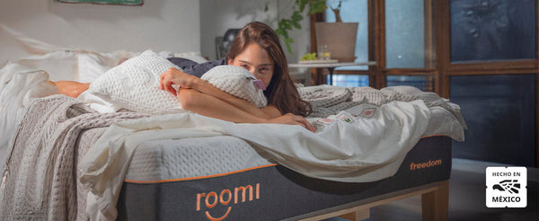 Mujer recostada abrazando una almohada sobre el colchón Roomi Freedom.